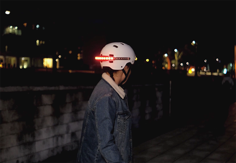 A lady using a Firefly at night while riding a skateboard